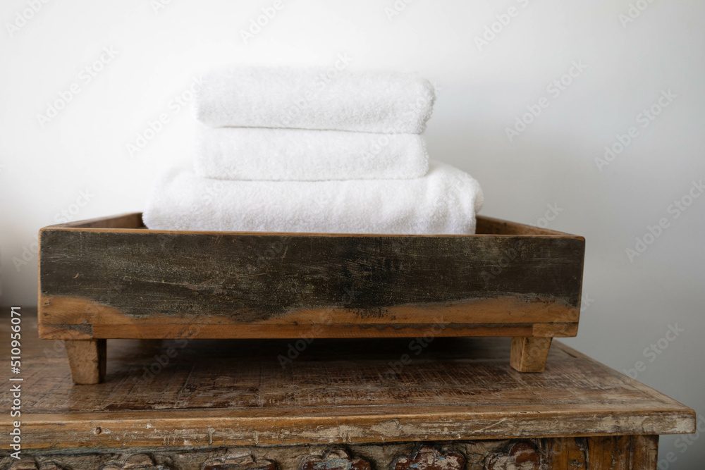 Pile of white towels carefully folded and placed in a wood tray