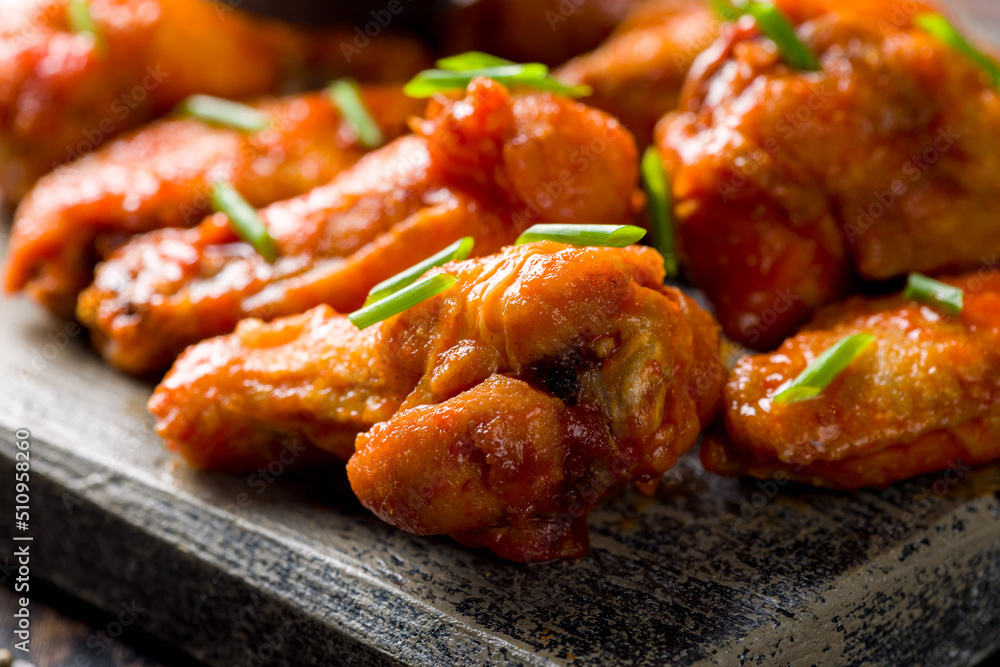 Buffalo chicken wings with green onion on the board extreme macro close up Buffalo chicken wings with green onion on the board extreme macro close up