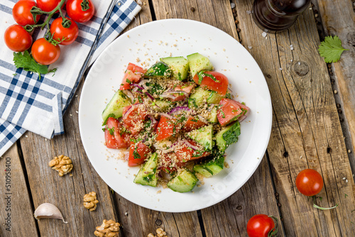 фотографія vegetable salad with tomatoes, cucumbers and walnuts top view on wooden table ge