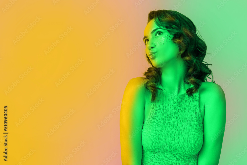 Toned portrait of beautiful young woman with glitters on her face against colorful background Toned portrait of beautiful young woman with glitters on her face against colorful background