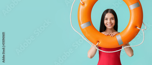 Female beach rescuer holding lifebuoy on light blue background with space for text