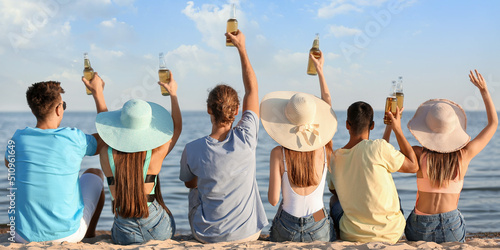 Happy friends drinking beer on sea beach