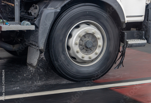 Detail of the wheel of a truck driving in the rain on a wet road.