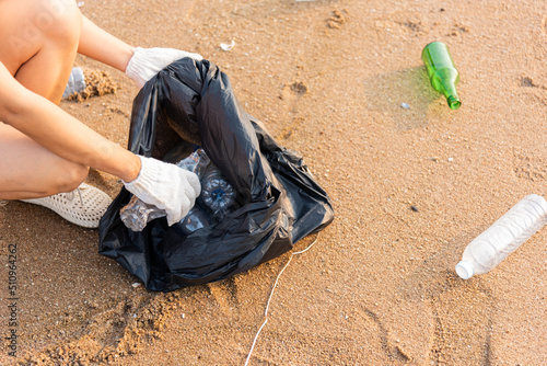 Volunteer woman picking plastic bottle into trash plastic bag black for cleaning the beach, female clean up garbage, Ecology concept and World Environment Day, Save earth concept © sorapop