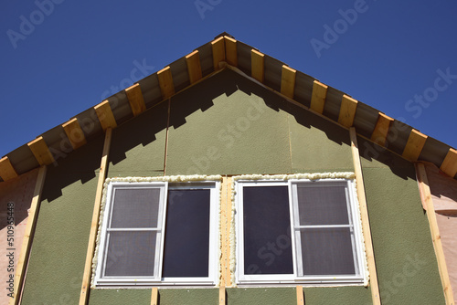 Wall covering of the frame house with panels of vinyl siding. construction or reconstruction, repair of the house. Installation of plastic Windows in a new residential building on blue sky background.