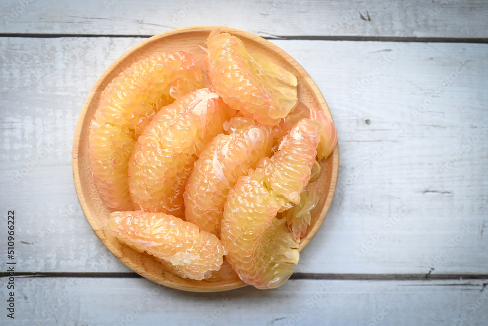 Pomelo fruit on wooden plate, fresh pomelo peeled frome pomelo tree , pummelo , grapefruit in summer tropical fruit in thailand - top view Pomelo fruit on wooden plate, fresh pomelo peeled frome pomelo tree , pummelo , grapefruit in summer tropical fruit in thailand - top view