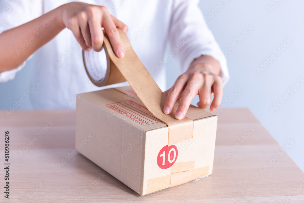 Woman's hand using masking tape to cover the parcel box