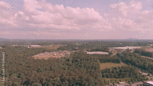 aerial footage of vast miles of lush green trees with buildings nestled in between and cars driving on the highway with powerful clouds and blue sky at Olde Rope Mill Park in Woodstock Georgia USA photo