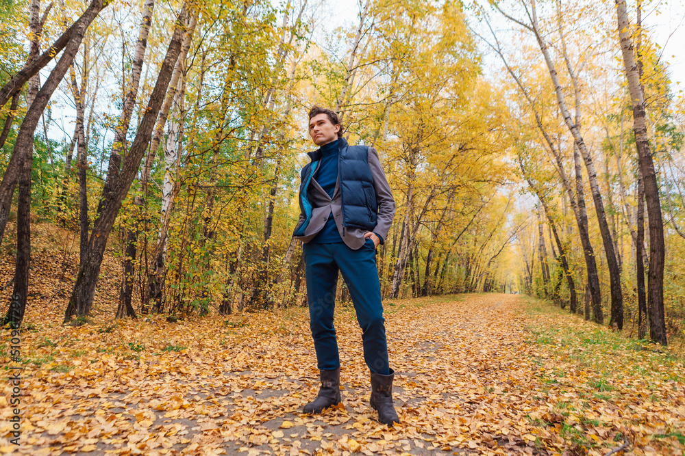 Tall handsome man walking in the autumn alley