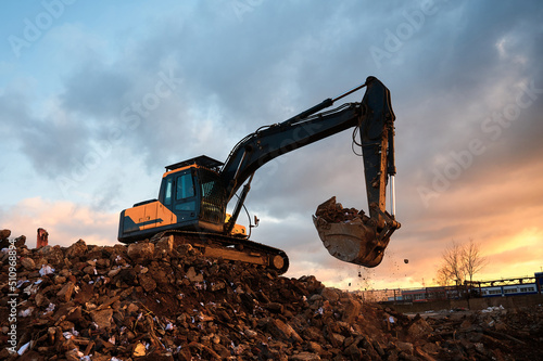 Building excavator with bucket stands on concrete waste