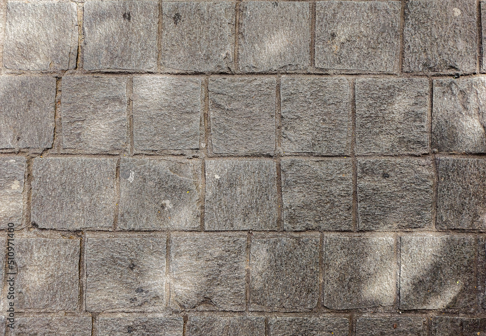 Fototapeta premium Granite cobblestoned pavement background. Stone pavement texture. Abstract background of cobblestone pavement close-up