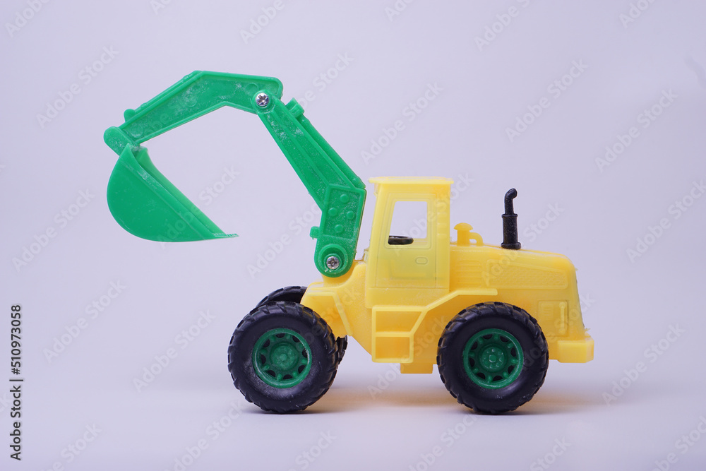 Side view of excavator model toy, green and yellow color, with studio lighting background