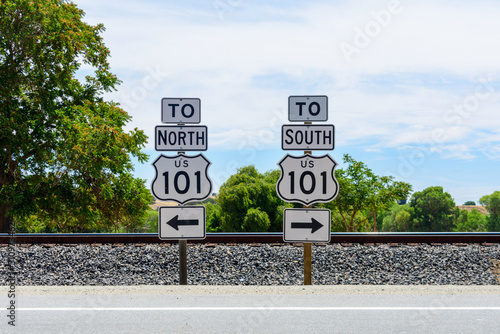 US Highway 101 directional signs. North and South freeway road signs. Background railroad tracks and green trees. photo