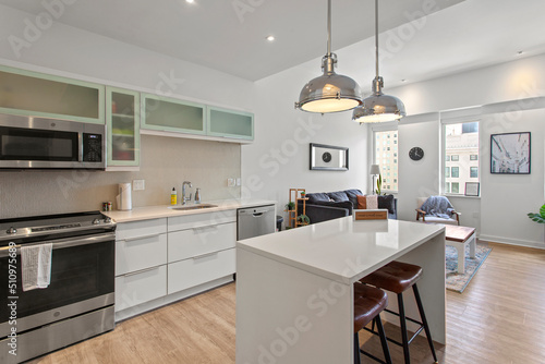 beautiful kitchen in new luxury home with island, pendant lights, hardwood floors, and stainless steel appliances © samiam2007