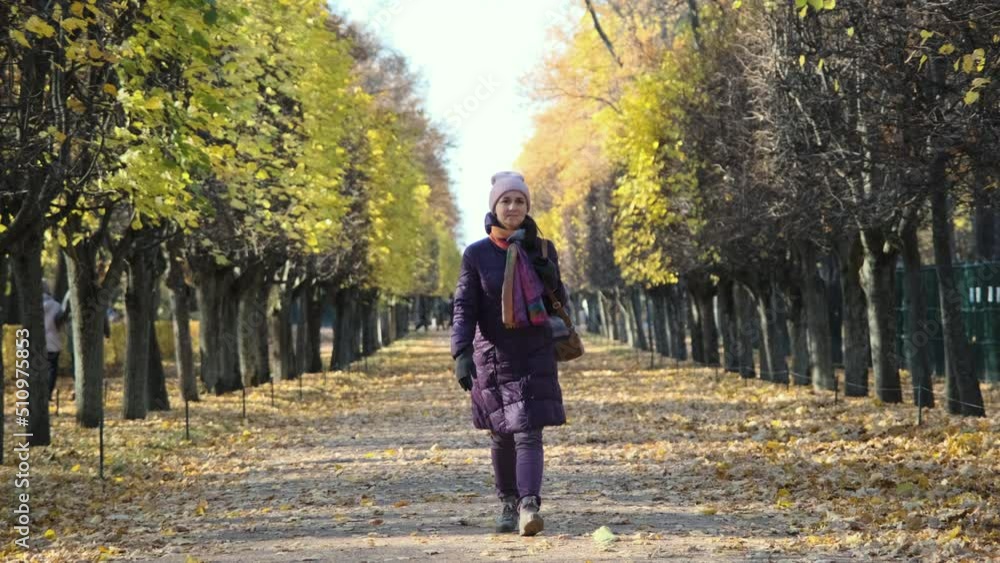 Young trendy woman walking in beautiful autumn park in sunny october day. Slow motion. Fall season, autumn atmosphere concept Young trendy woman walking in beautiful autumn park in sunny october day. Slow motion. Fall season, autumn atmosphere concept
