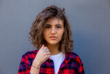 Portrait of young sensual woman with curly hair in red shirt on grey background