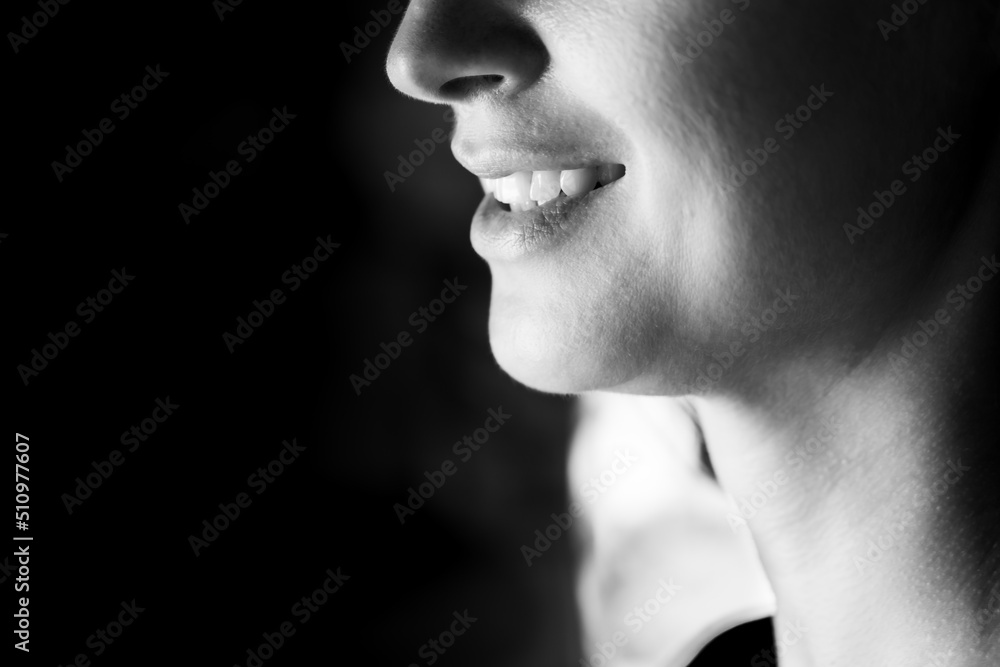 BW photo of an attractive woman. A large portrait on a dark background. Macro photo, bottom part of the face. Front view.