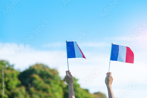 Tela hand holding France flag on blue sky background