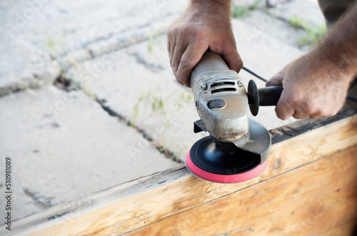 man polishing a board with a manual grinder, close-up