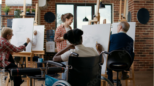 Young woman with disability learning to draw sketch on canvas, attending art class lesson with teacher for personal growth. Person in wheelchair drawing vase model to develop new skills.