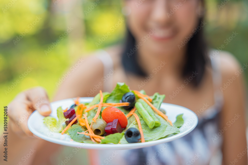 Close up of woman raised a plate of vegetable salad. Girl enjoy salad for lunch, wellbeing diet concept. Concept of health Close up of woman raised a plate of vegetable salad. Girl enjoy salad for lunch, wellbeing diet concept. Concept of health