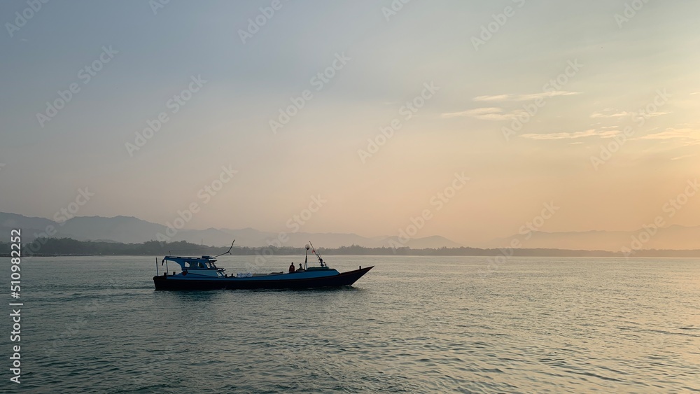 Silhouette of a traditional fishing boat speeding on the sea in the morning