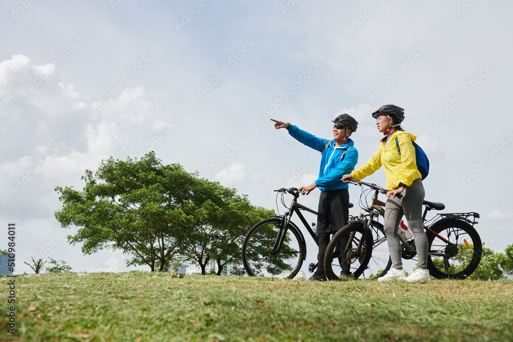 Couple on bicycles standing on hill and deciding where to ride Couple on bicycles standing on hill and deciding where to ride