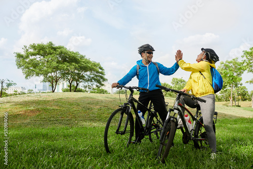 Joyful friends giving each other high five after finishing coming to destination point on bicycles
