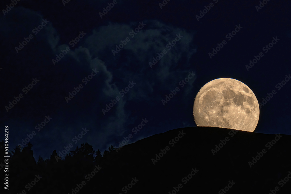 Fototapeta premium beautiful moonrise over the mountains with tree silhouettes on the horizon