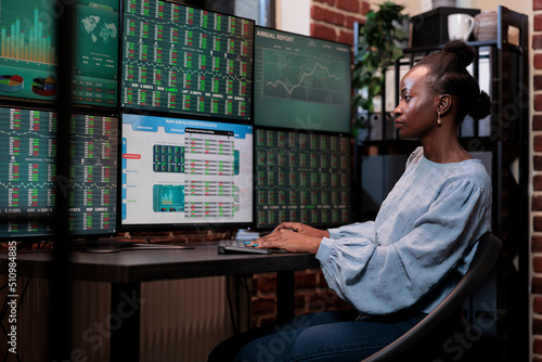 Fotografija Brokerage agency agent sitting at multi monitor workstation while trading risk free assets
