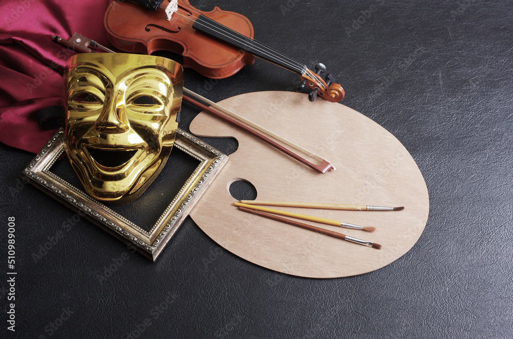 Art attributes. Painting, music, theater. Art palette and brushes, violin and comedy theatrical mask. Dark background. - obrazy, fototapety, plakaty 