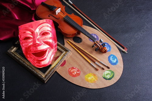 Art attributes. Painting, music, theater. Art palette and brushes, violin and comedy theatrical mask. Dark background.