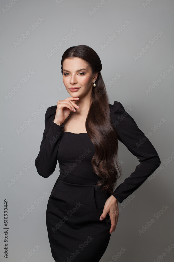 Glamorous brunette model in elegant black dress standing on white background Glamorous brunette model in elegant black dress standing on white background