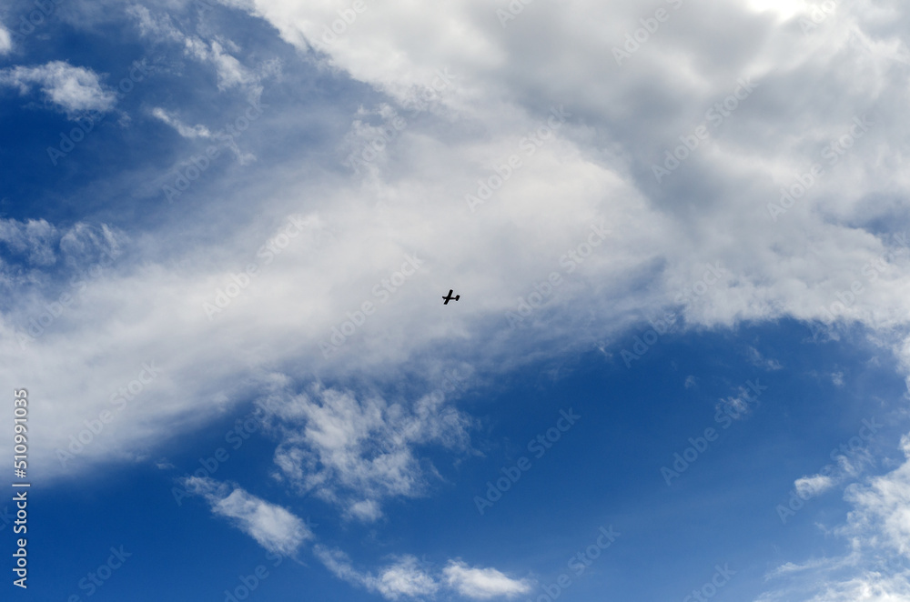 a small plane flies far in the sky on a clear summer day