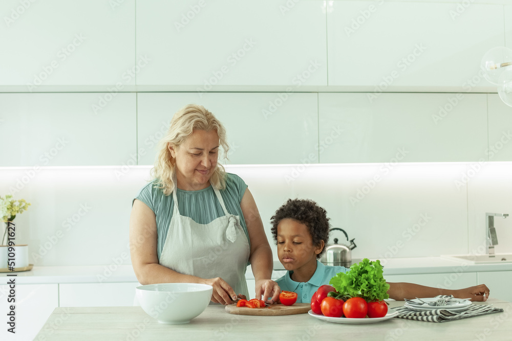 Mother and son preparing vegetable together in kitchen at home
