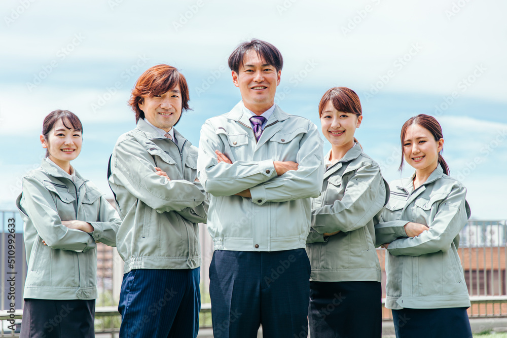 作業着をきた笑顔のビジネスマン・ビジネスウーマン（5人・腕組み）
