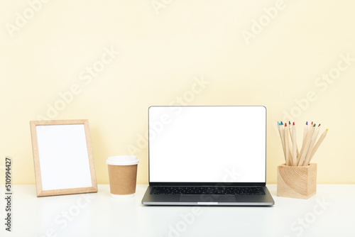 Concept of workplace on white table with blank laptop and photo frame