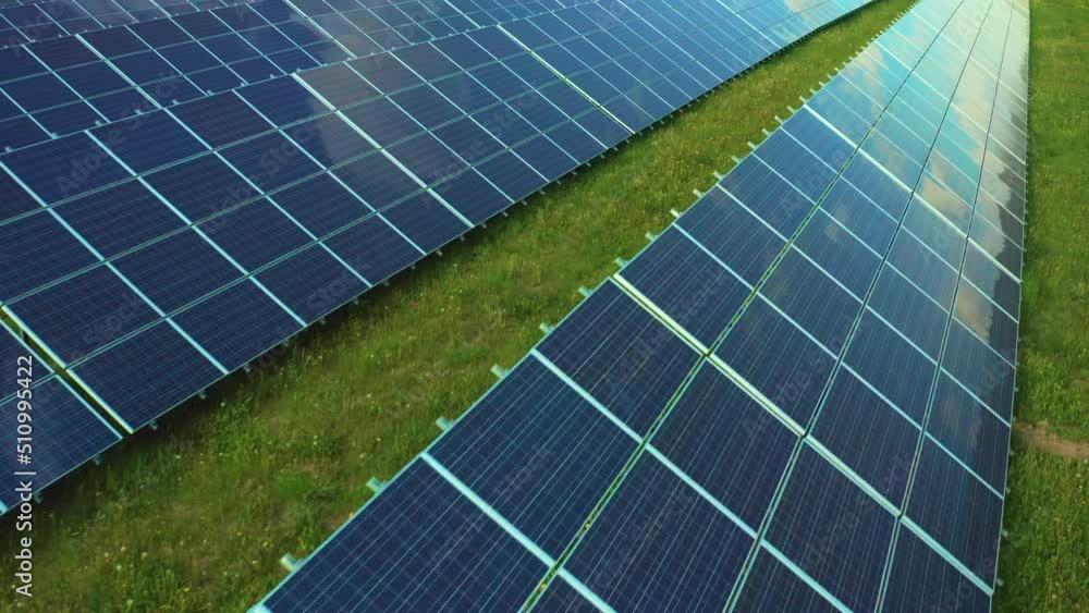 Futuristic solar panels with sky reflected on surface built on grass in countryside. Photovoltaic cells generate alternative energy at station close view Futuristic solar panels with sky reflected on surface built on grass in countryside. Photovoltaic cells generate alternative energy at station close view