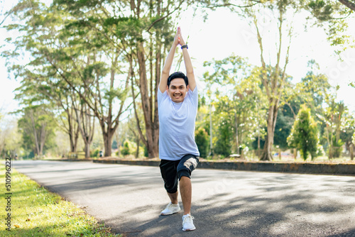 Young Asian man doing stretching exercise, preparing for running in the nature. Healthy lifestyle © Sewupari Studio