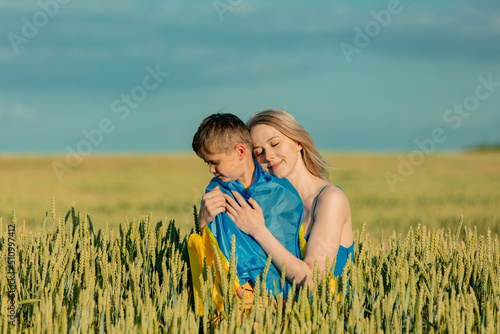 Mother with son in ukrainian flag in wheat field