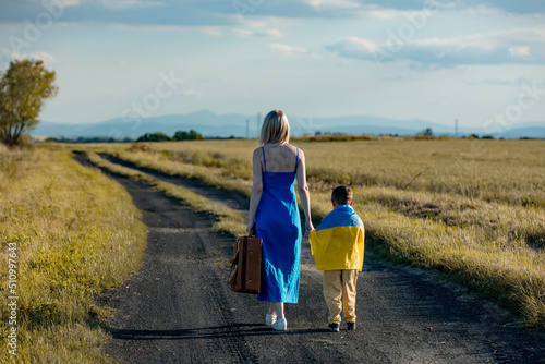 Mother with son in ukrainian flag walking on country road