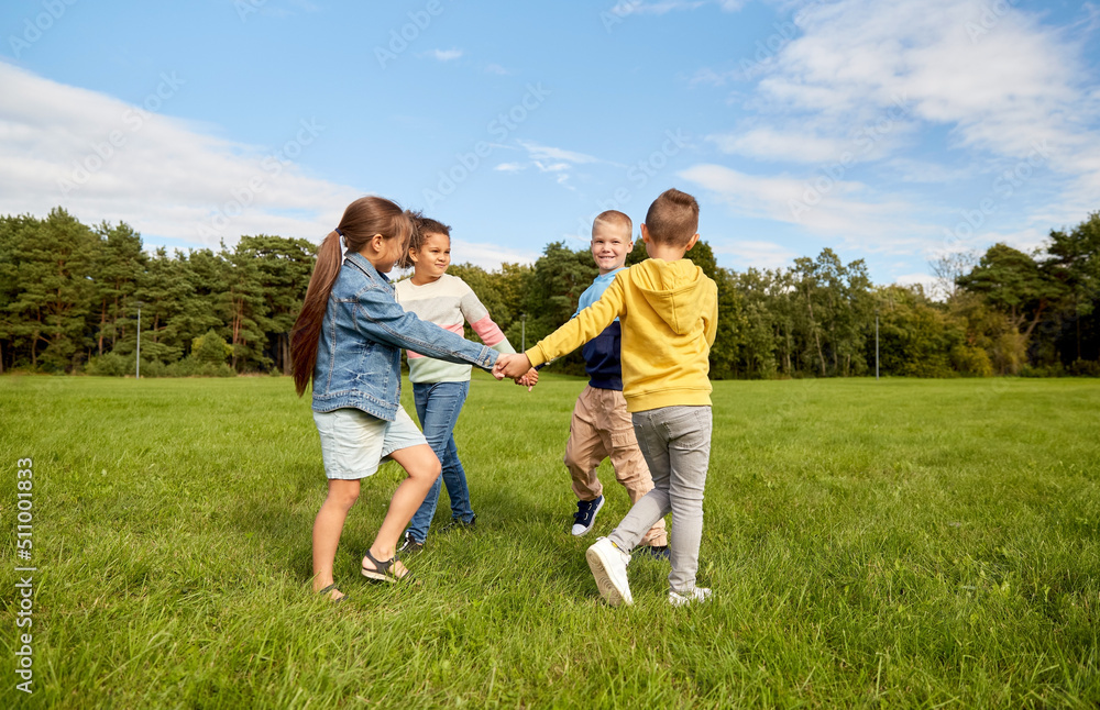 childhood, leisure and people concept - group of happy kids playing round dance at park childhood, leisure and people concept - group of happy kids playing round dance at park