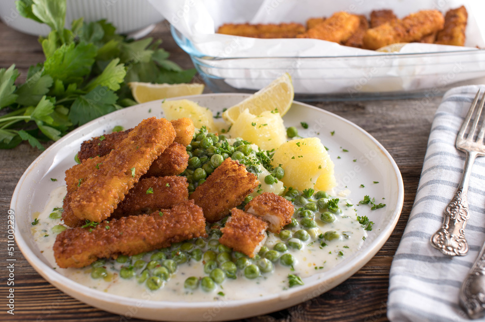 Fish sticks with peas, boiled potatoes and bechamel sauce on a plate Fish sticks with peas, boiled potatoes and bechamel sauce on a plate