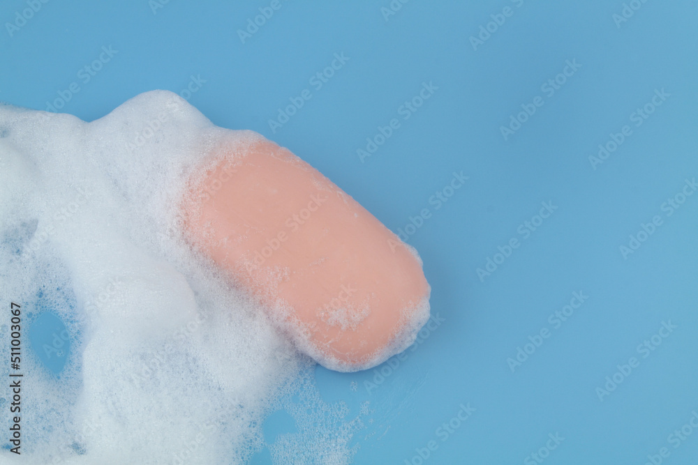 Fototapeta premium Pink soap and foam on blue background, copy space for text.