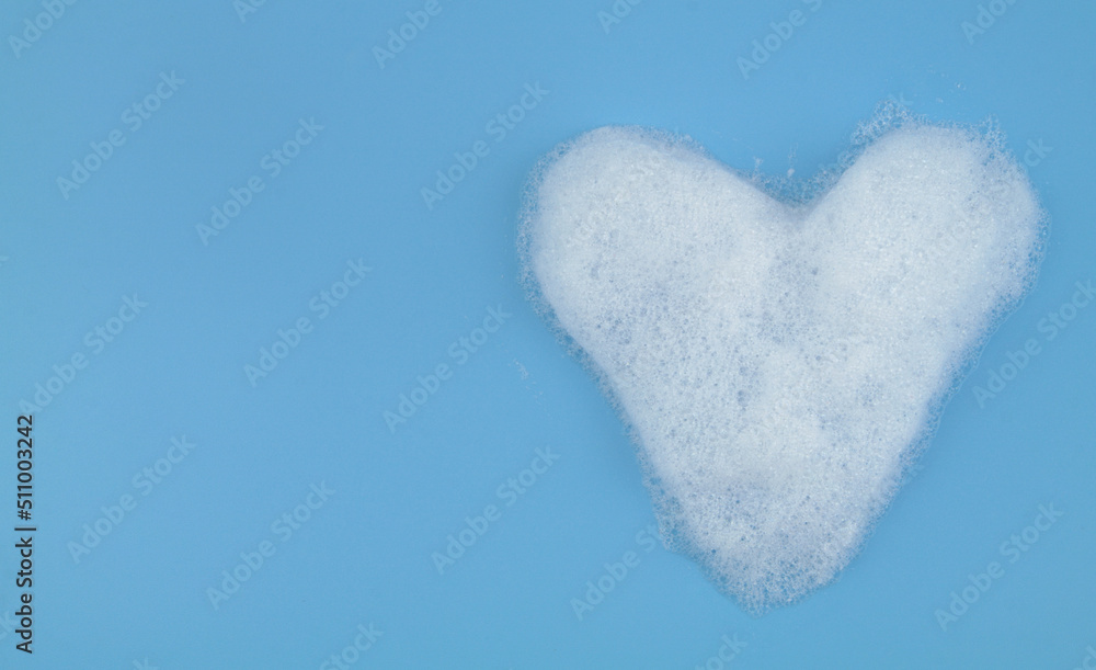 Obraz premium Heart from foam bubbles on blue background with room for text. Softness and love concept.
