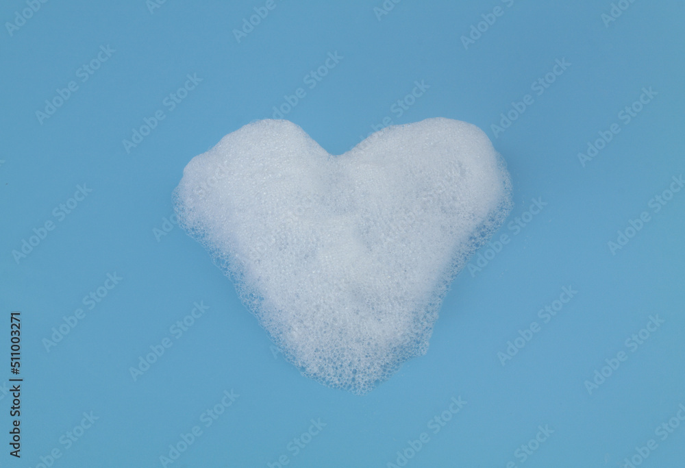 Heart shaped soap foam bubbles on blue background. Clean, health care and romance concept.	