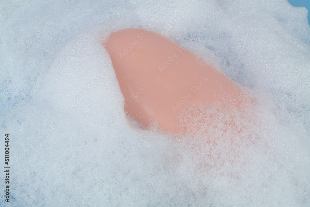 Fototapeta premium Pink soap bar on white foam close-up