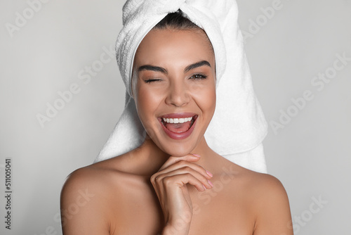 Beautiful young woman with towel on head against light background