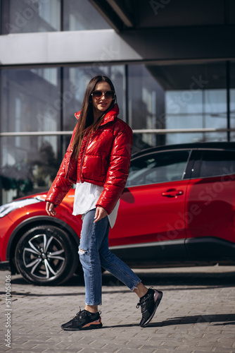 Woman standing by her new red car © Petro