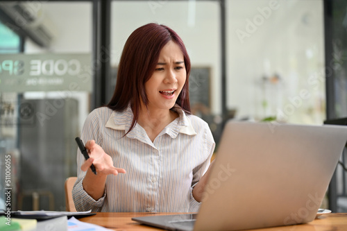 Unhappy asian businesswoman dissatisfied and getting angry after reading a business email